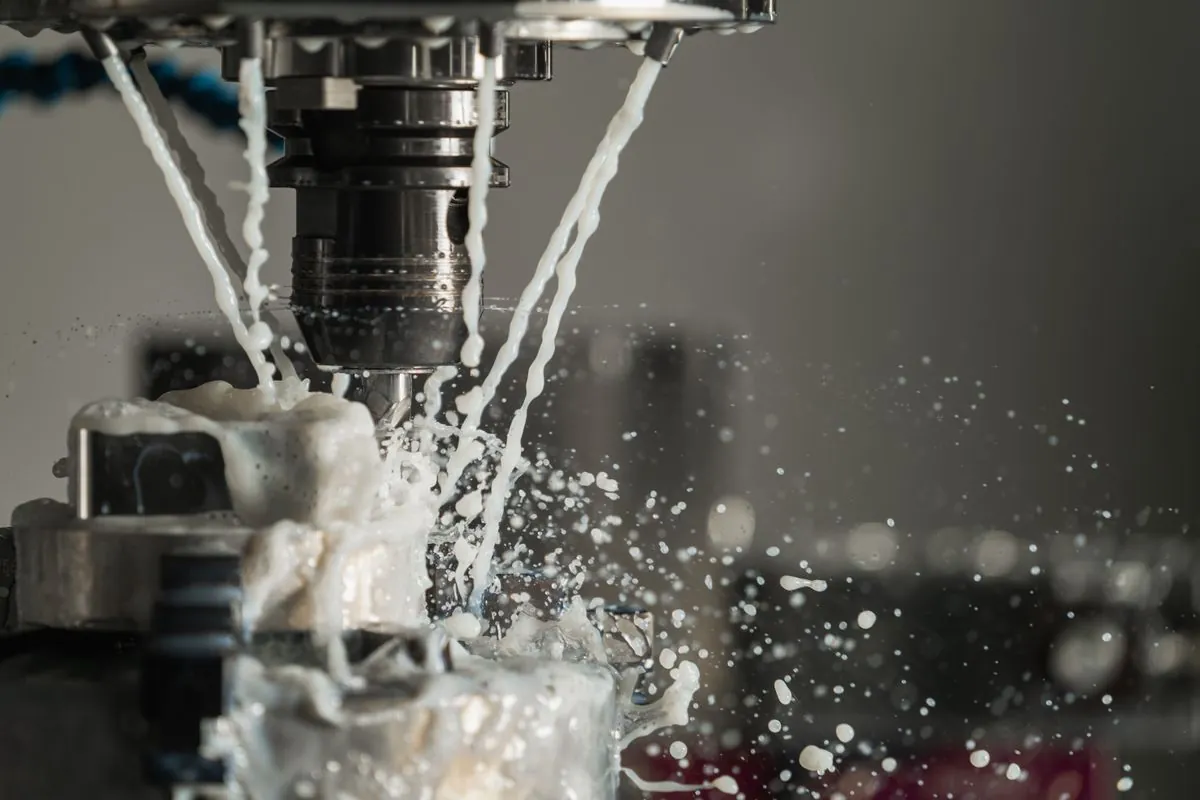 Coolant spraying from a CNC milling cutter as it cuts into a metal part